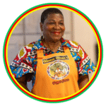 Smiling woman in colorful attire and apron, standing confidently.
